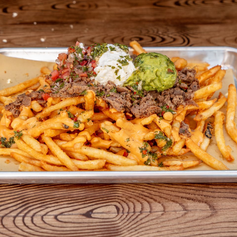 Loaded fries with cheese sauce, ground beef, pico de gallo, sour cream, and guacamole.